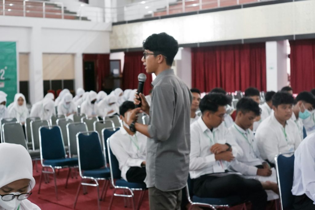 a man speaking into a microphone in front of a group of people
